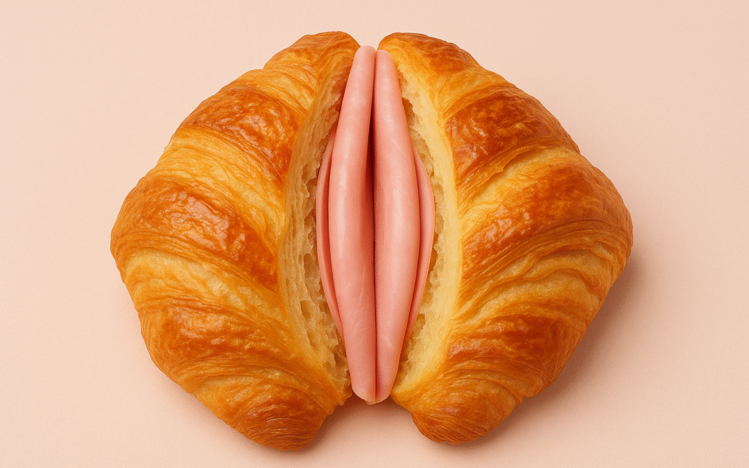 Croissant partido por la mitad con relleno de jamón sobre fondo rosa claro, simbolizando de forma artística la vulva femenina