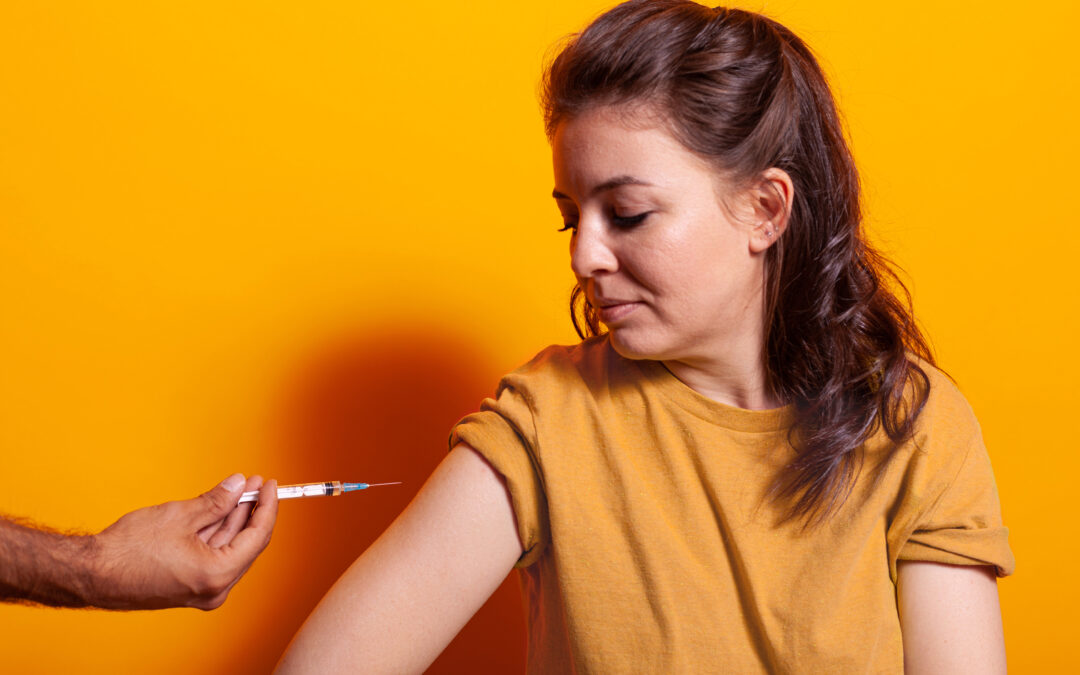 Mujer observando la aplicación de una inyección intramuscular en el brazo, representando el uso de anticonceptivos hormonales inyectables
