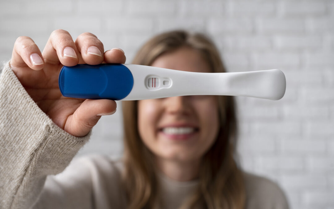 Prueba de embarazo positiva con doble línea sostenida por una mujer joven feliz