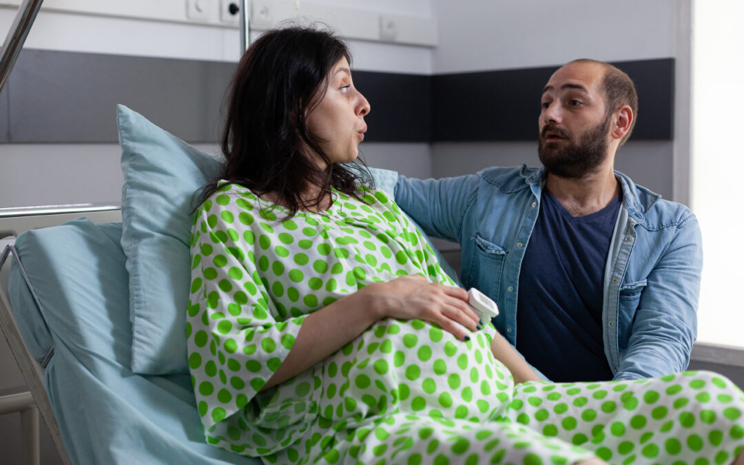 Mujer embarazada acompañada de su pareja en una cama hospitalaria, durante el trabajo de parto