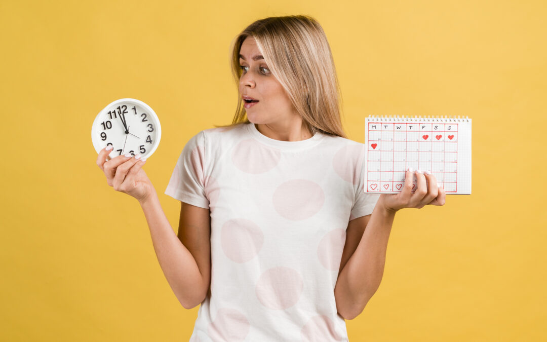 Mujer joven con expresión de sorpresa mira un reloj y un calendario menstrual, simbolizando el control del ciclo sin menstruar