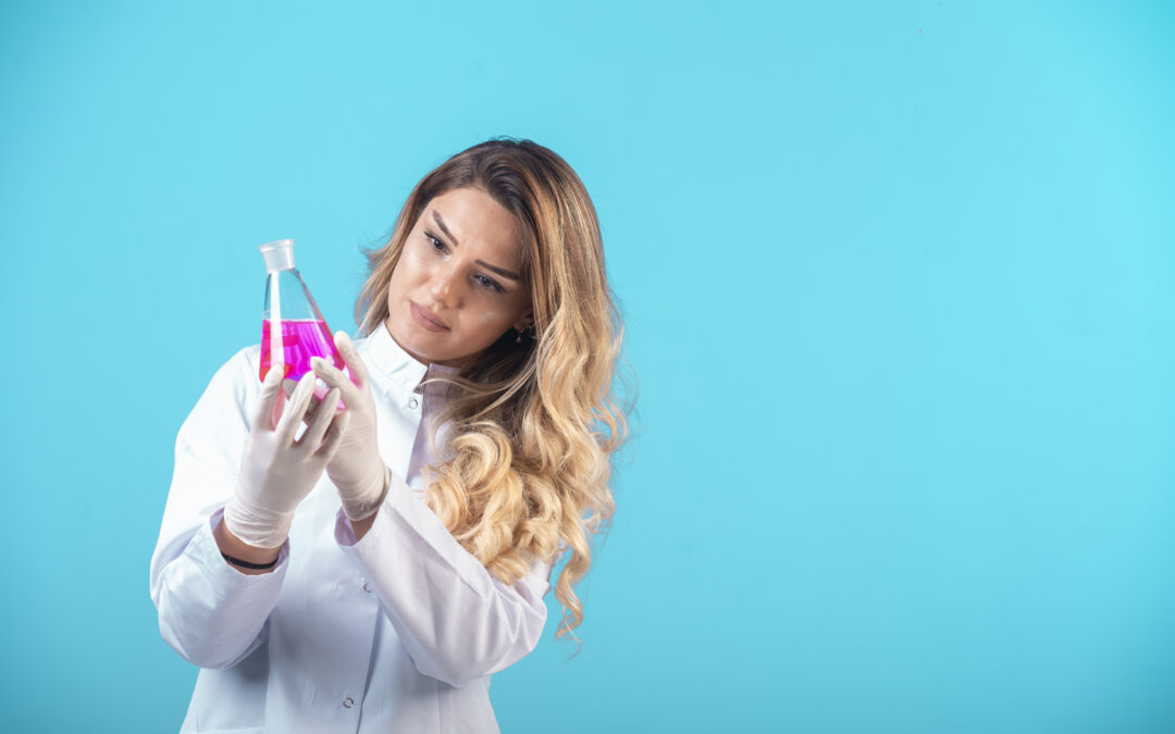 Científica en laboratorio observa un matraz con líquido rosa, representando la investigación en terapia génica como futuro tratamiento contra la endometriosis