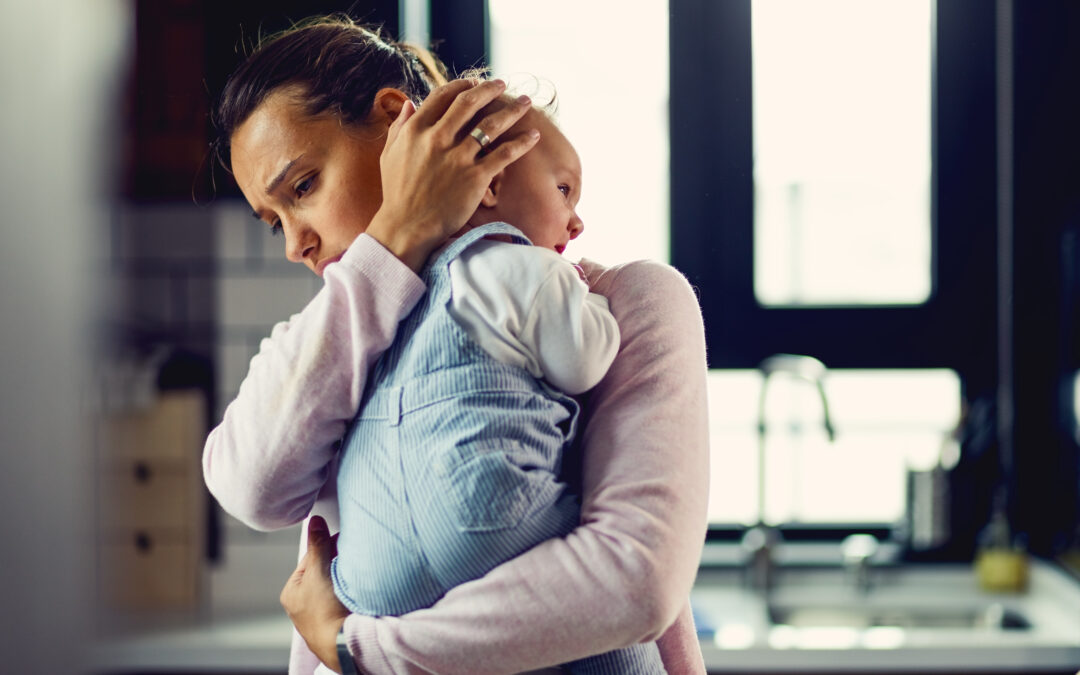 Madre con expresión de preocupación abrazando a su bebé en casa, representando la depresión posparto y la importancia del apoyo médico y emocional en Quito