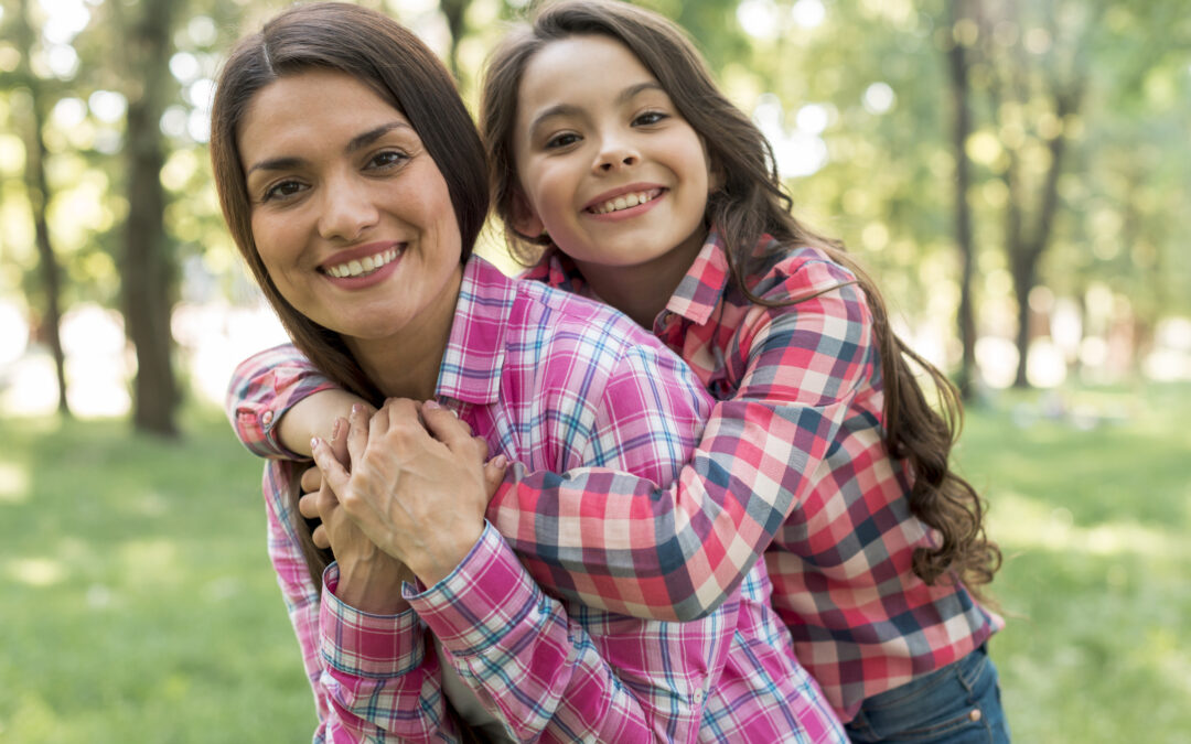 Madre e hija sonrientes en un parque, simbolizando una conversación natural y sin tabúes sobre la menstruación y la educación menstrual en Quito