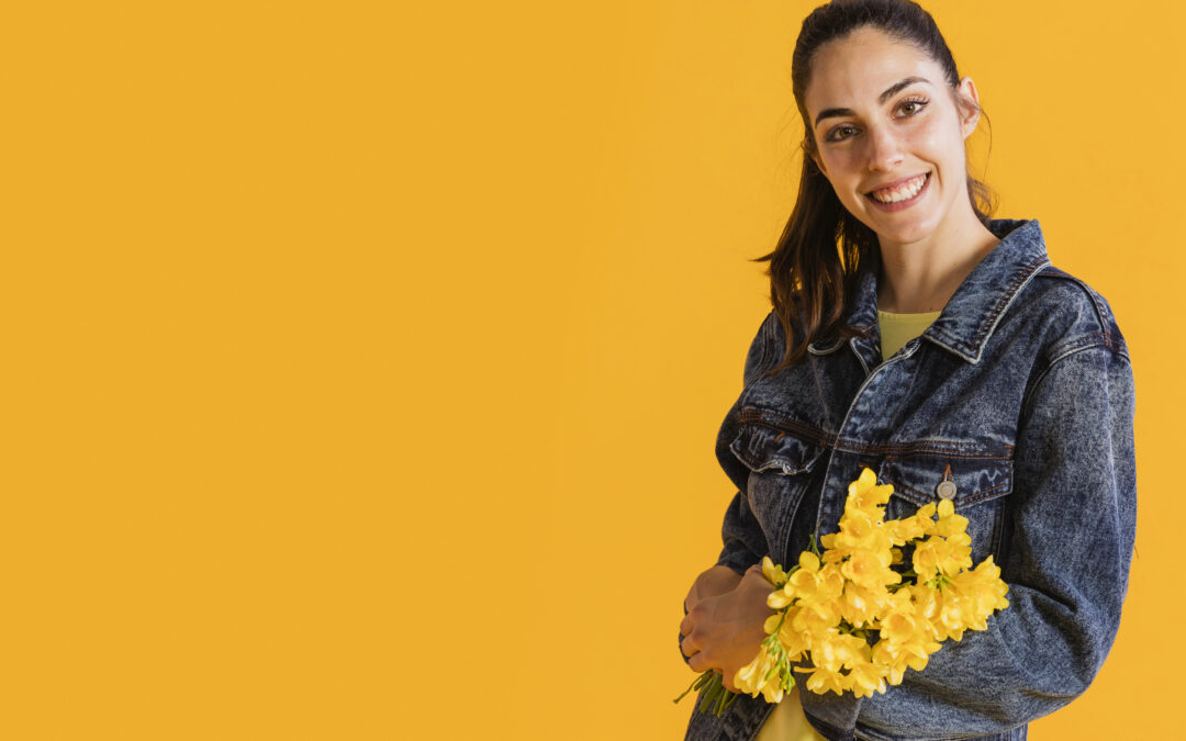 Mujer sonriente sosteniendo flores amarillas que representan salud y bienestar femenino, imagen ilustrativa del control ginecológico anual en Quito con el Dr. Denis Sánchez.